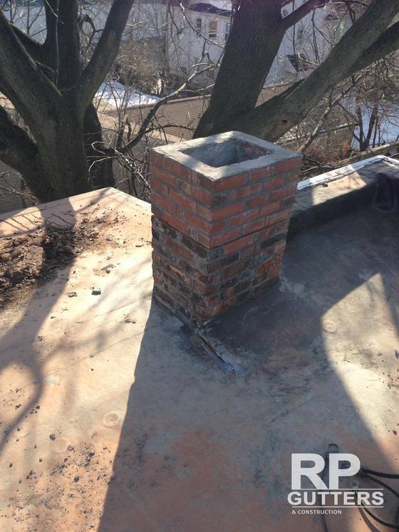 Brick chimney flashed into a flat roof