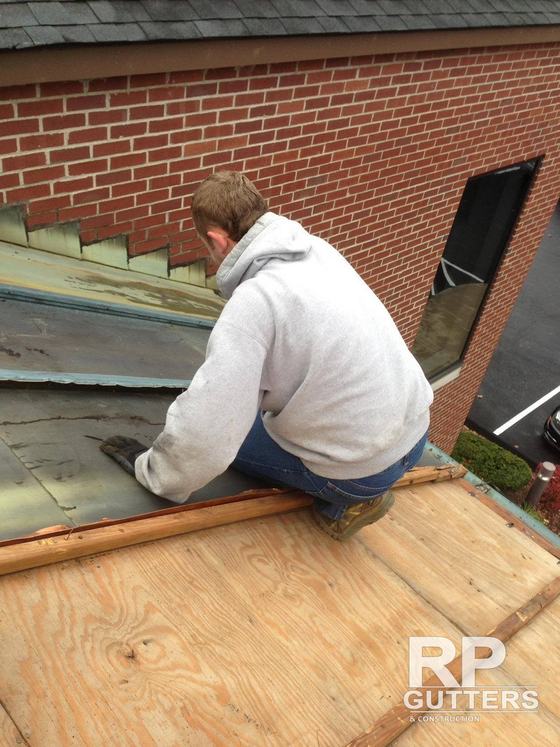 Installer fitting metal flashing at a brick wall