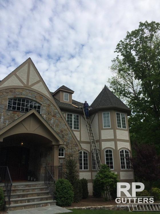 Tudor-style home with a worker on a ladder