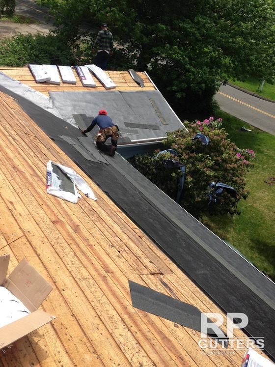Roofer laying underlayment on a new roof deck