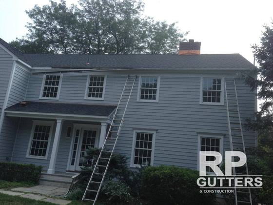 Ladders set at a gray colonial for gutter work